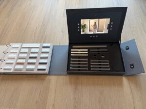 DUETTE® Collectieboek met stofstalen naast het scherm met de AI-video
